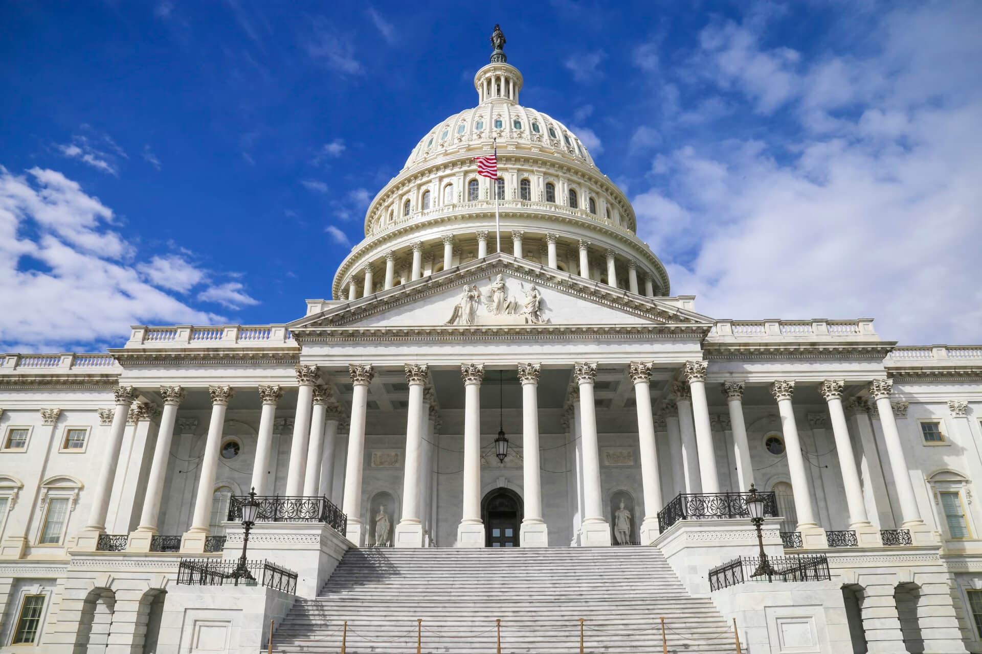 United States Capitol building in Washington D.C. with blue sky and American flag